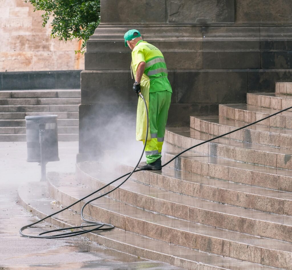 pexels-photo-14965464-14965464 A street worker pressure washes stone stairs in a public park, ensuring cleanliness and safety.
